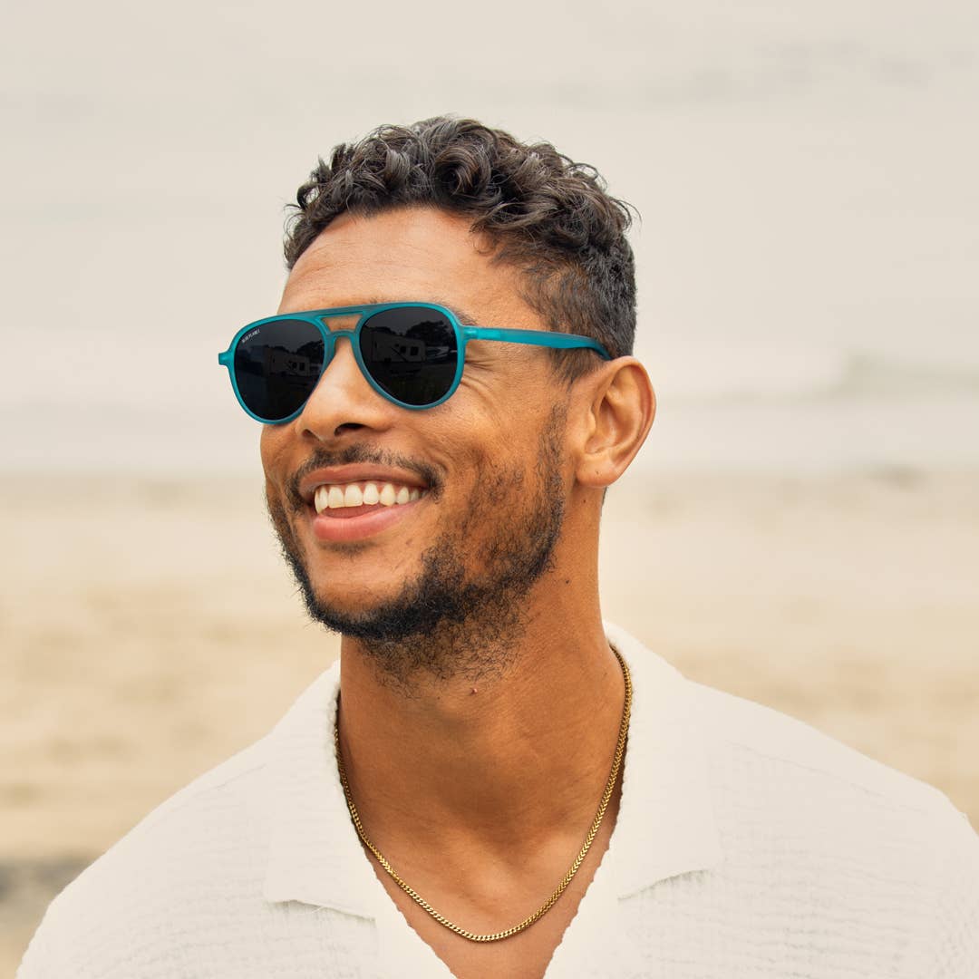 Man wearing teal sunglasses with a blurred background