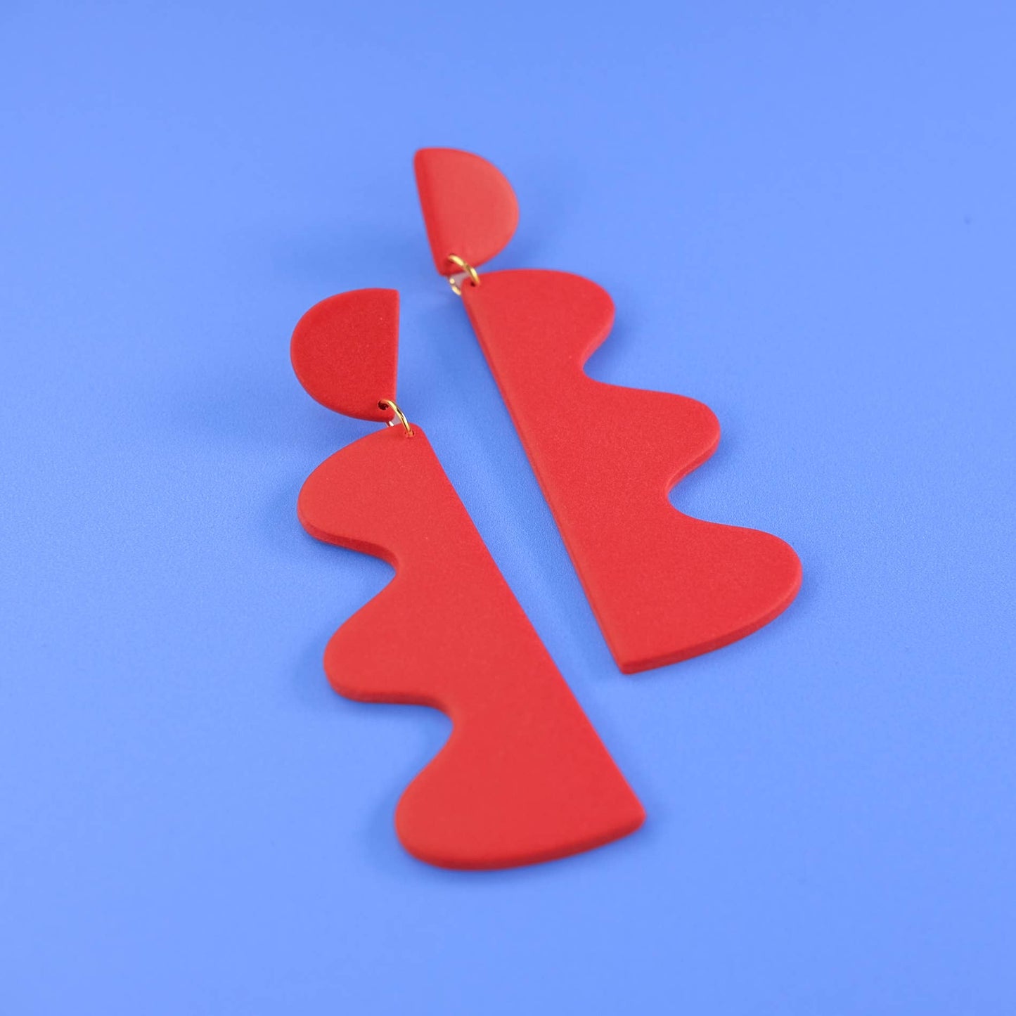 Red abstract earrings on a blue background