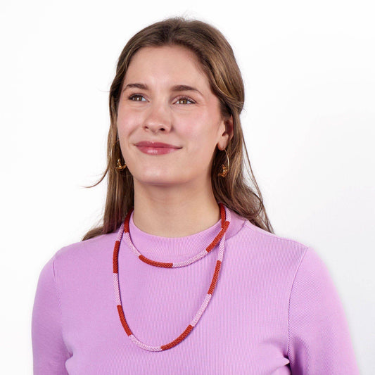 Woman wearing a pink sweater and red beaded necklace on a white background