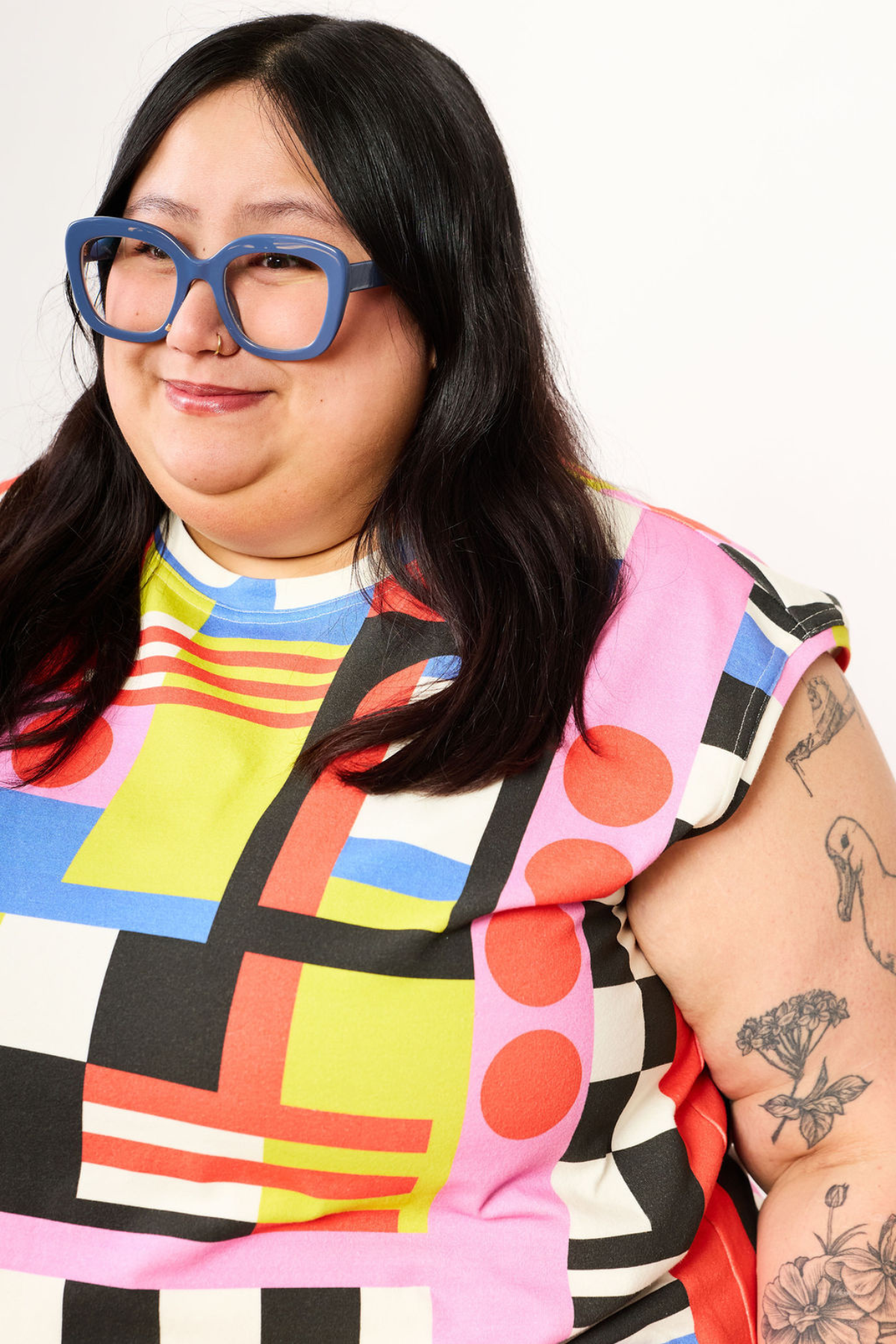 Person wearing a colorful, patterned outfit with blue glasses against a white background