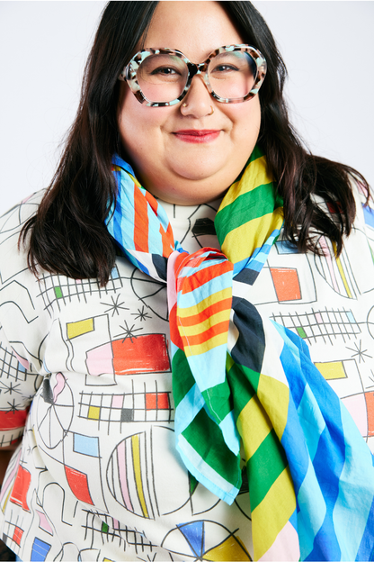Person wearing a colorful organic cotton scarf and colorful organic t-shirt against a white background