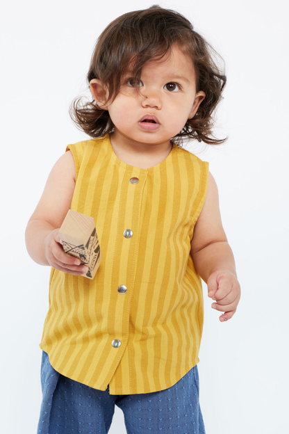 Child wearing a yellow striped sleeveless shirt with snaps on a white background