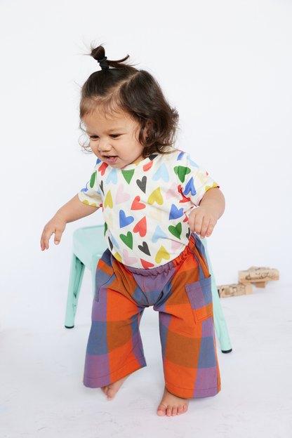 Child wearing a colorful outfit with heart patterns from Lilla Barn Clothing on a white background