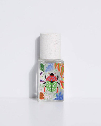 A small, clear bottle of eau de parfum with a colorful, floral design label. The cap is white.