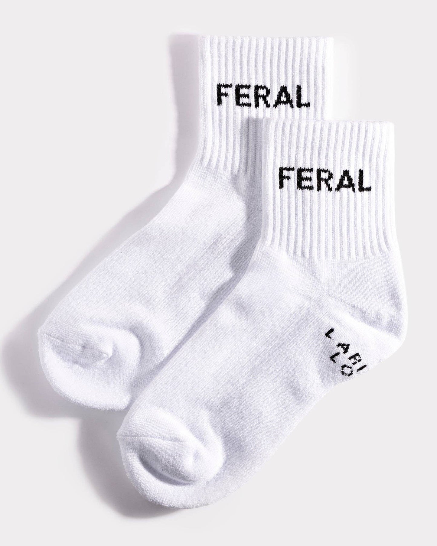 White socks with 'FERAL' branding on a light gray background