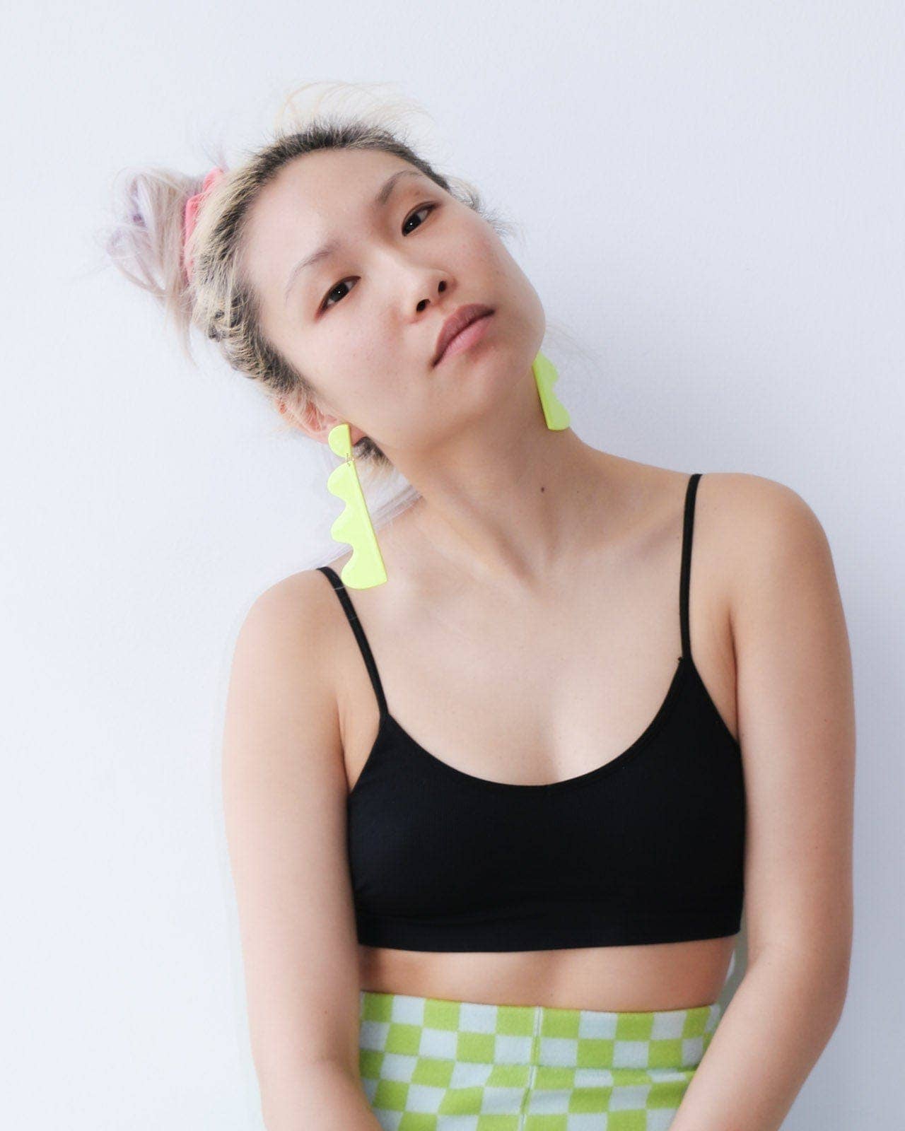 Person wearing a black sports bra and green checkered shorts against a white background