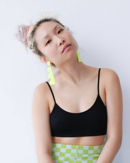 Person wearing a black sports bra and green checkered shorts against a white background