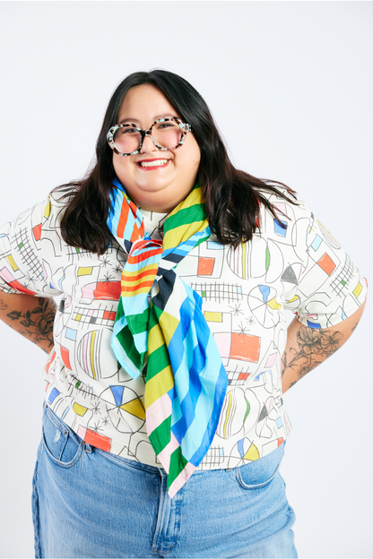 Person wearing a colorful organic cotton scarf and colorful organic t-shirt against a white background