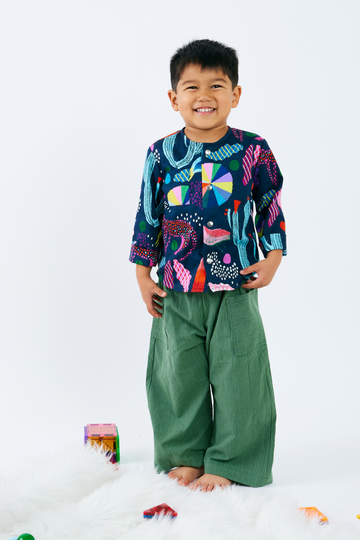 Child wearing a colorful shirt and green cotton striped pants on a white background