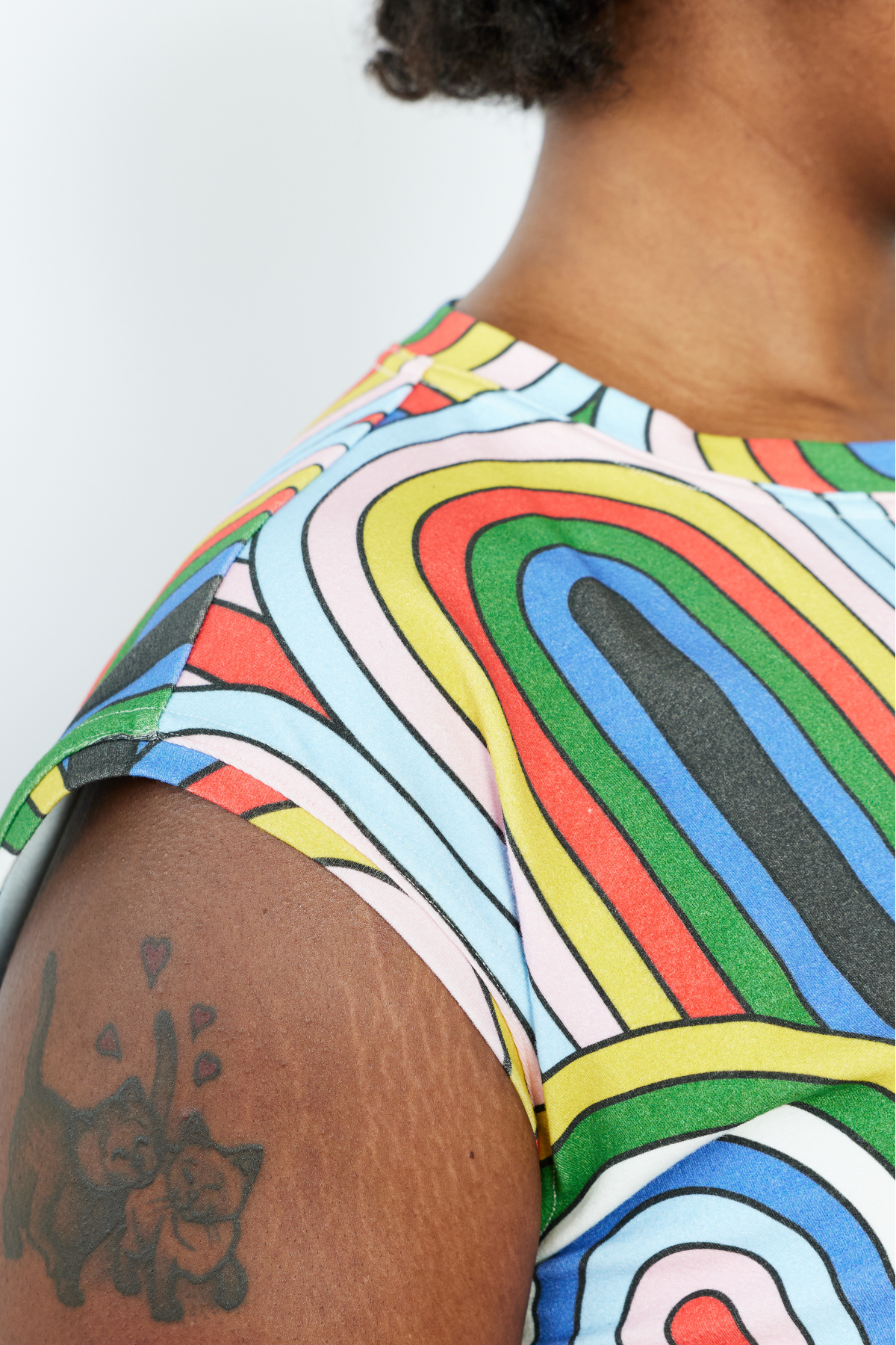 Person wearing a colorful patterned shirt with a tattoo on their arm.