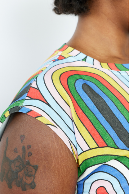 Person wearing a colorful patterned shirt with a tattoo on their arm.