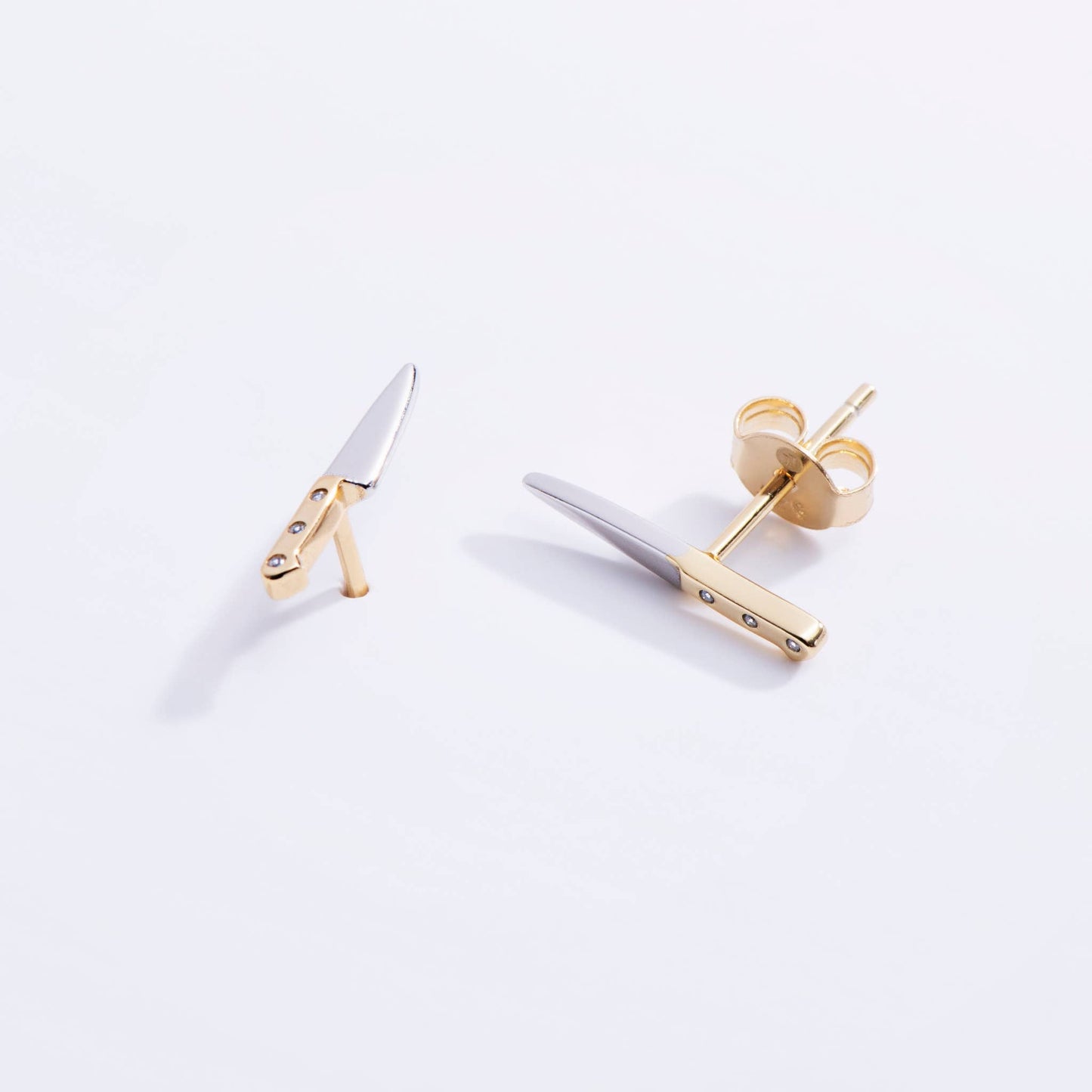 Gold and silver knife earrings on a white background