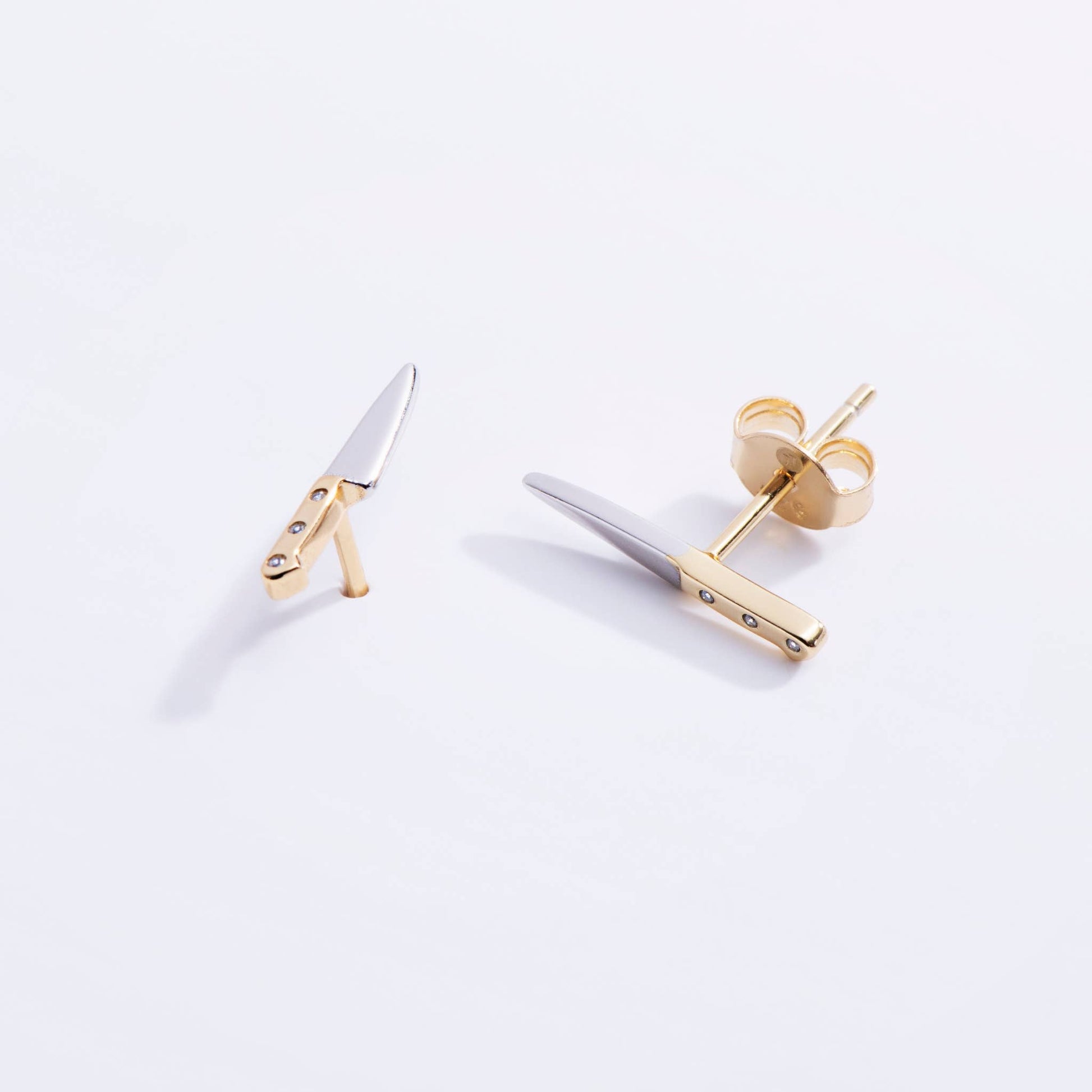 Gold and silver knife earrings on a white background