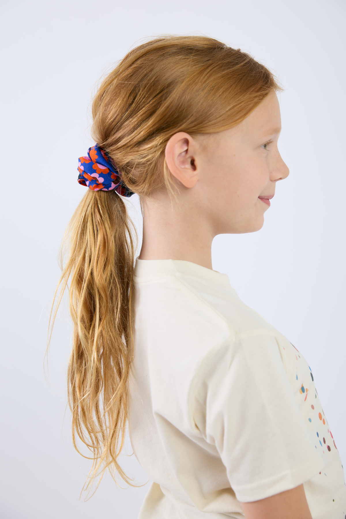 Girl with a colorful hair tie in her ponytail against a white background