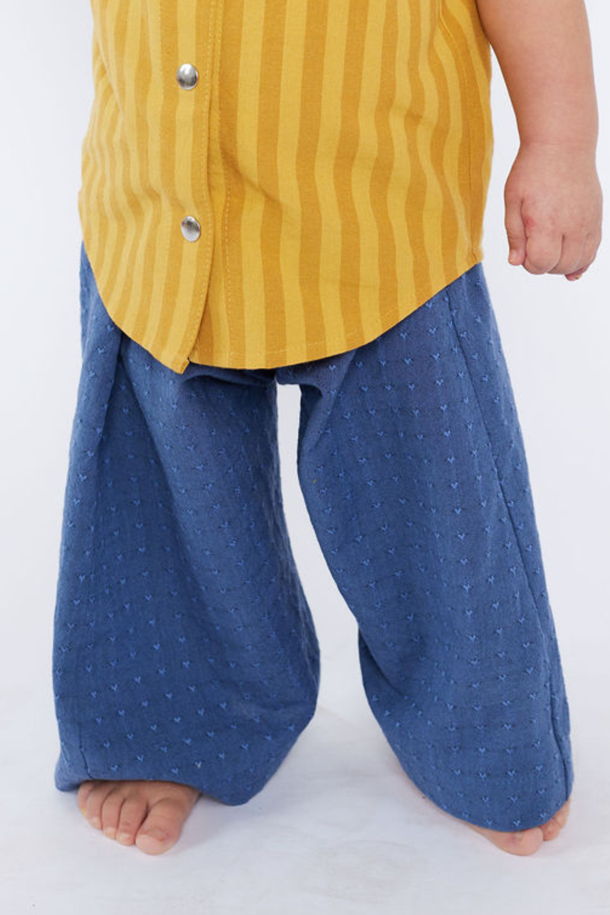 Child wearing a yellow striped shirt and blue pants on a white background