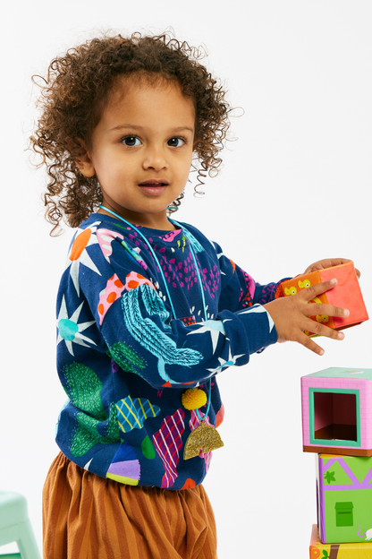 Child wearing a sustainable and soft kid top and striped pants by Lilla Barn Clothing