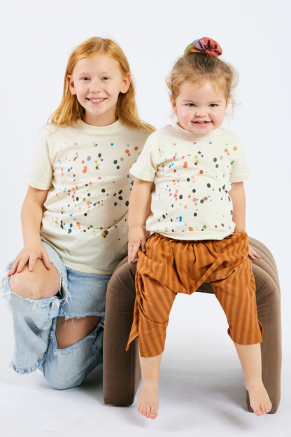 Two children wearing matching polka dot organic cotton kid shirts on a white background