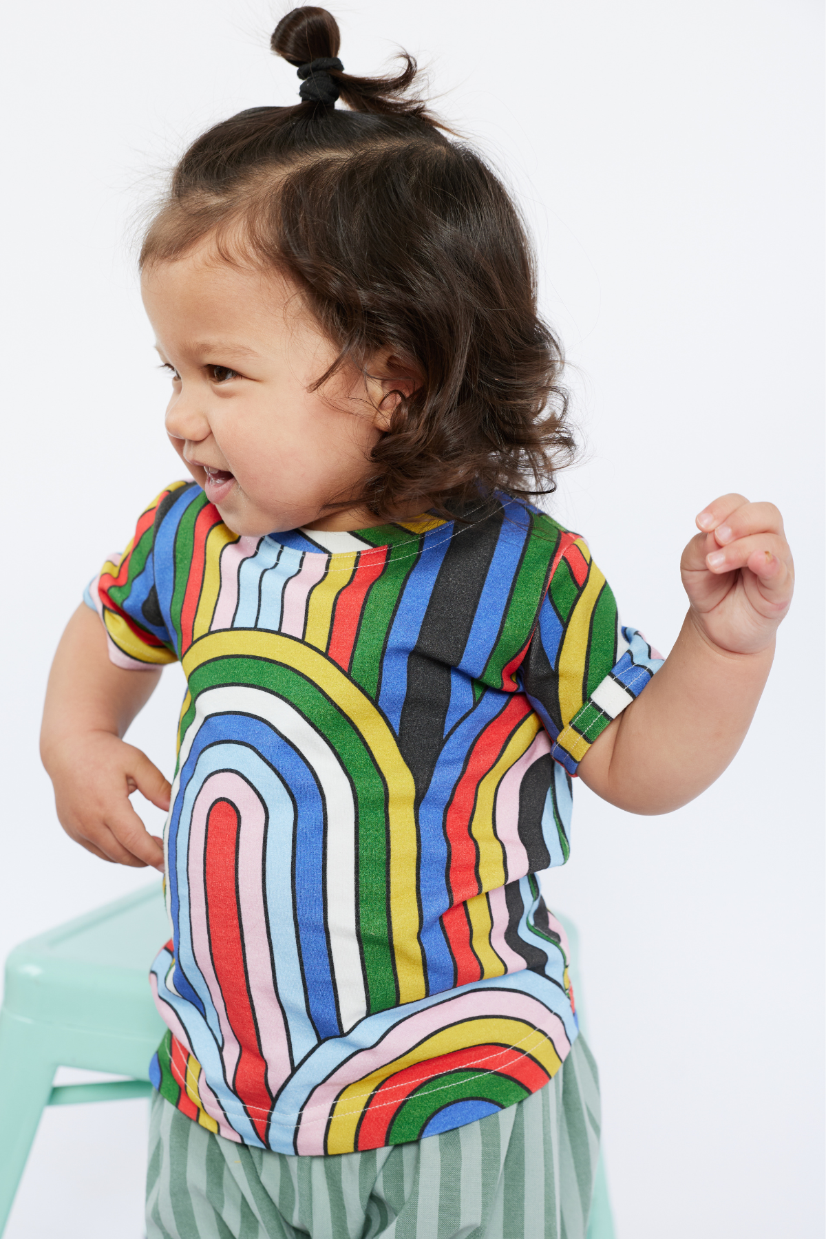 Child wearing a colorful striped shirt from Lilla Barn Clothing with a plain background