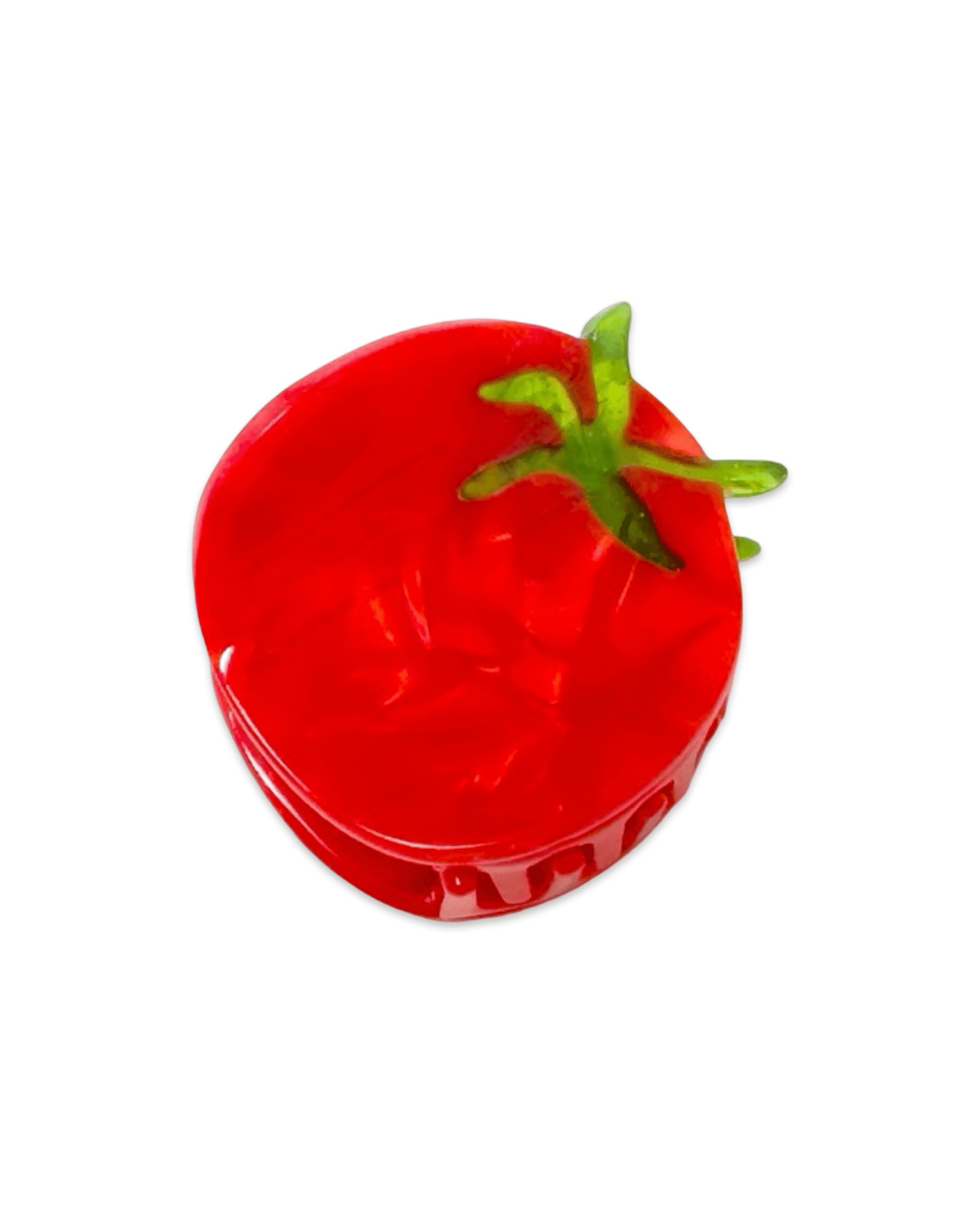 Red tomato-shaped hair clip with green stem on a white background