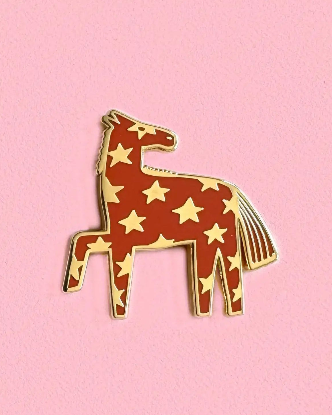 Pin with a design of a horse with star patterns on a pink background
