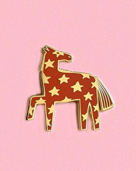 Pin with a design of a horse with star patterns on a pink background