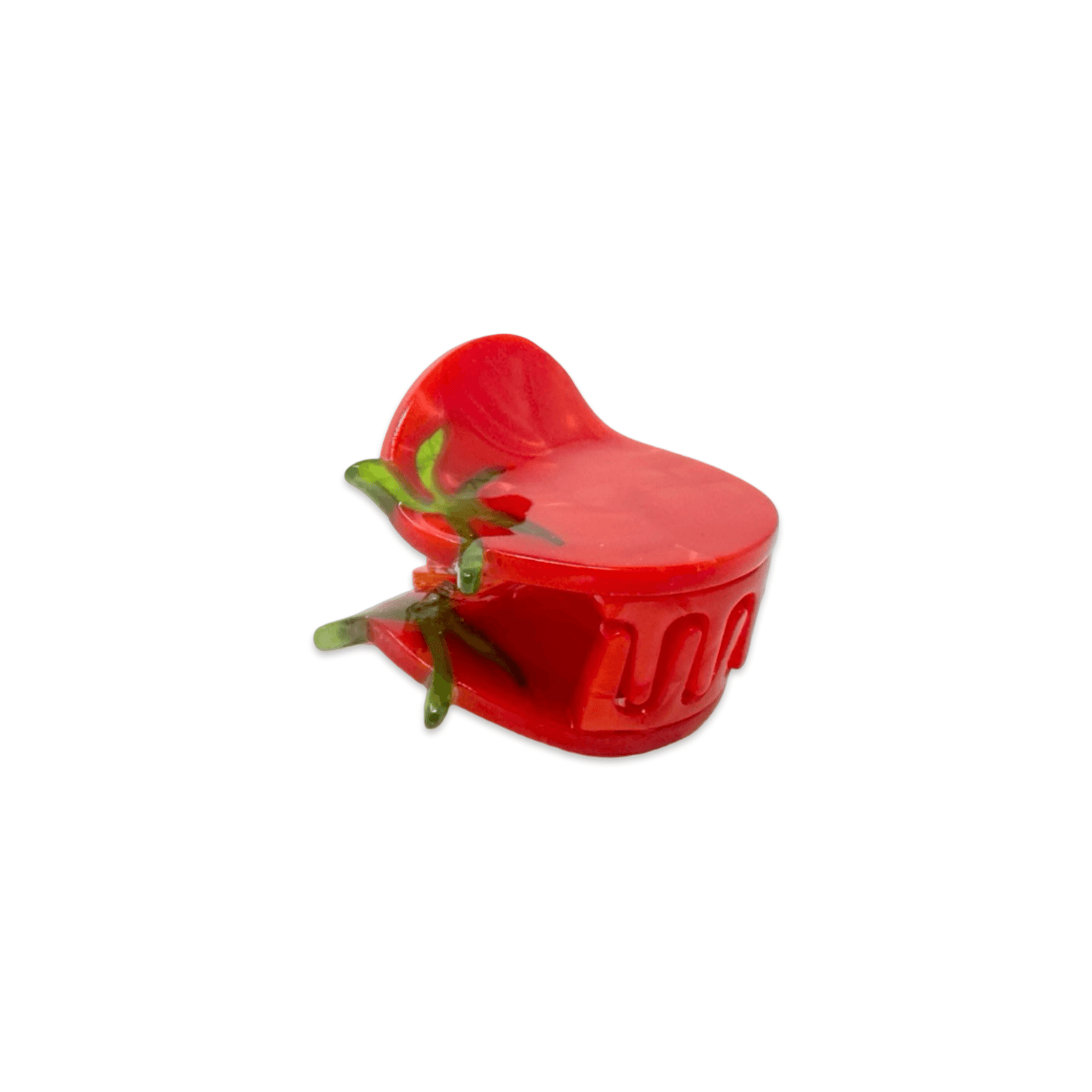 Red tomato-shaped hair clip with green leaves on a white background