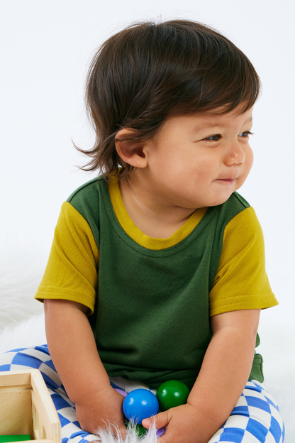 Baby wearing a green and yellow bamboo t-shirt with blue checkered organic cotton leggings.