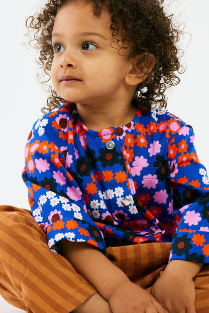 Child wearing a colorful floral shirt with a plain background