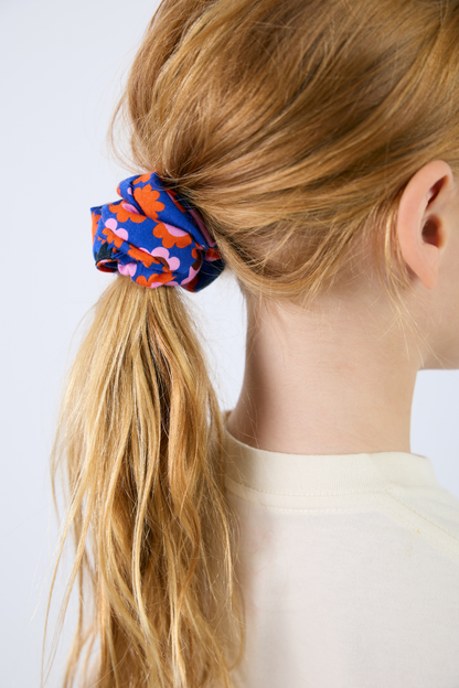 Person with a colorful scrunchie in their hair on a white background