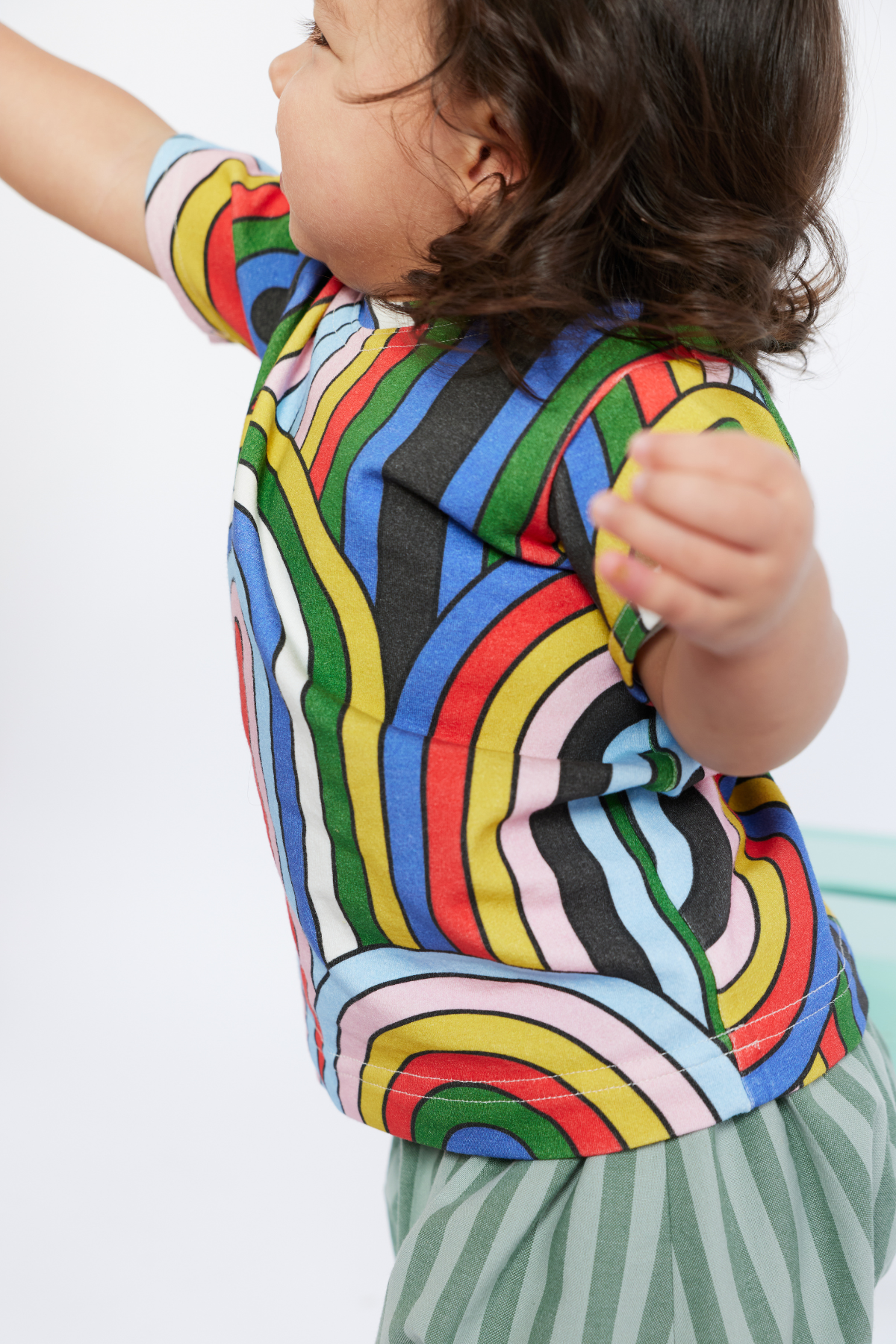 Child wearing a colorful striped shirt with a white background