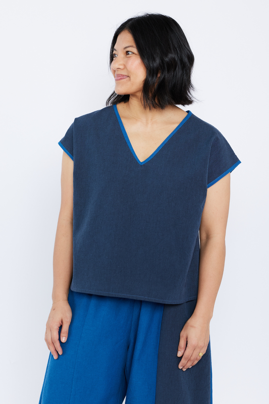 Woman wearing a blue top and pants against a white background
