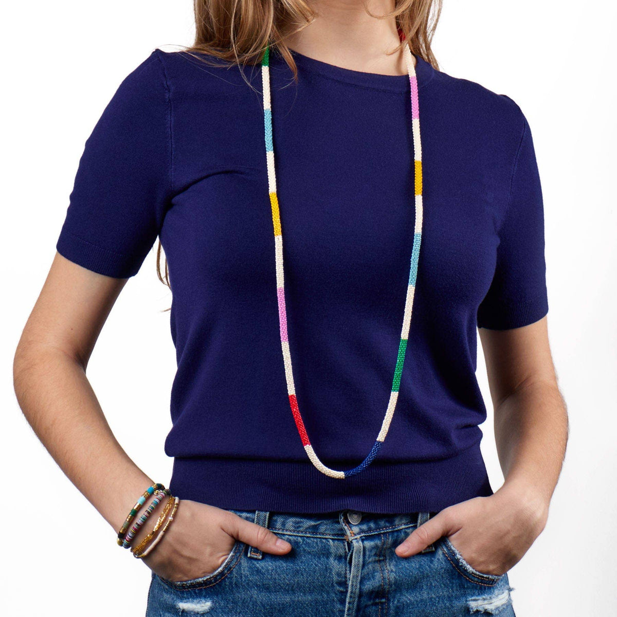 Person wearing a blue shirt with a colorful beaded necklace on a white background