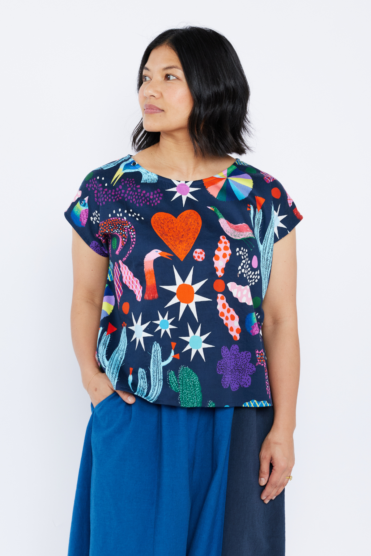 Woman wearing a colorful patterned top from Lilla Barn Clothing with a plain background