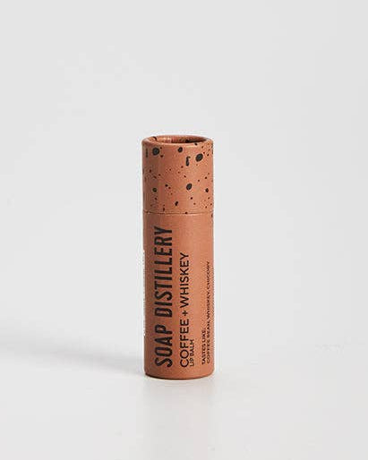 Moisturizing lip balm with coffee and whiskey scent in compostable packaging. 