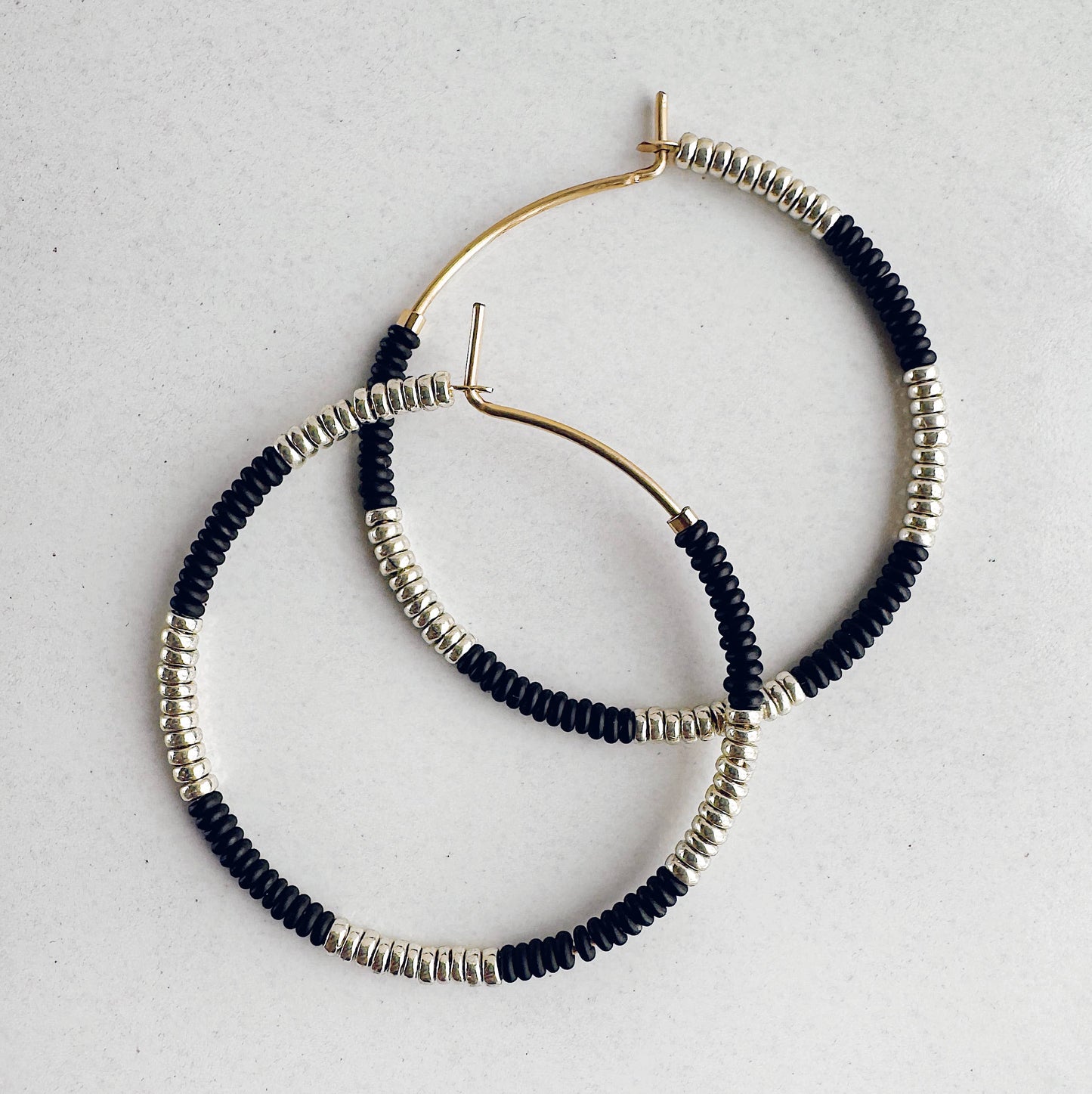 Hoop earrings with black and silver beads on a light gray background