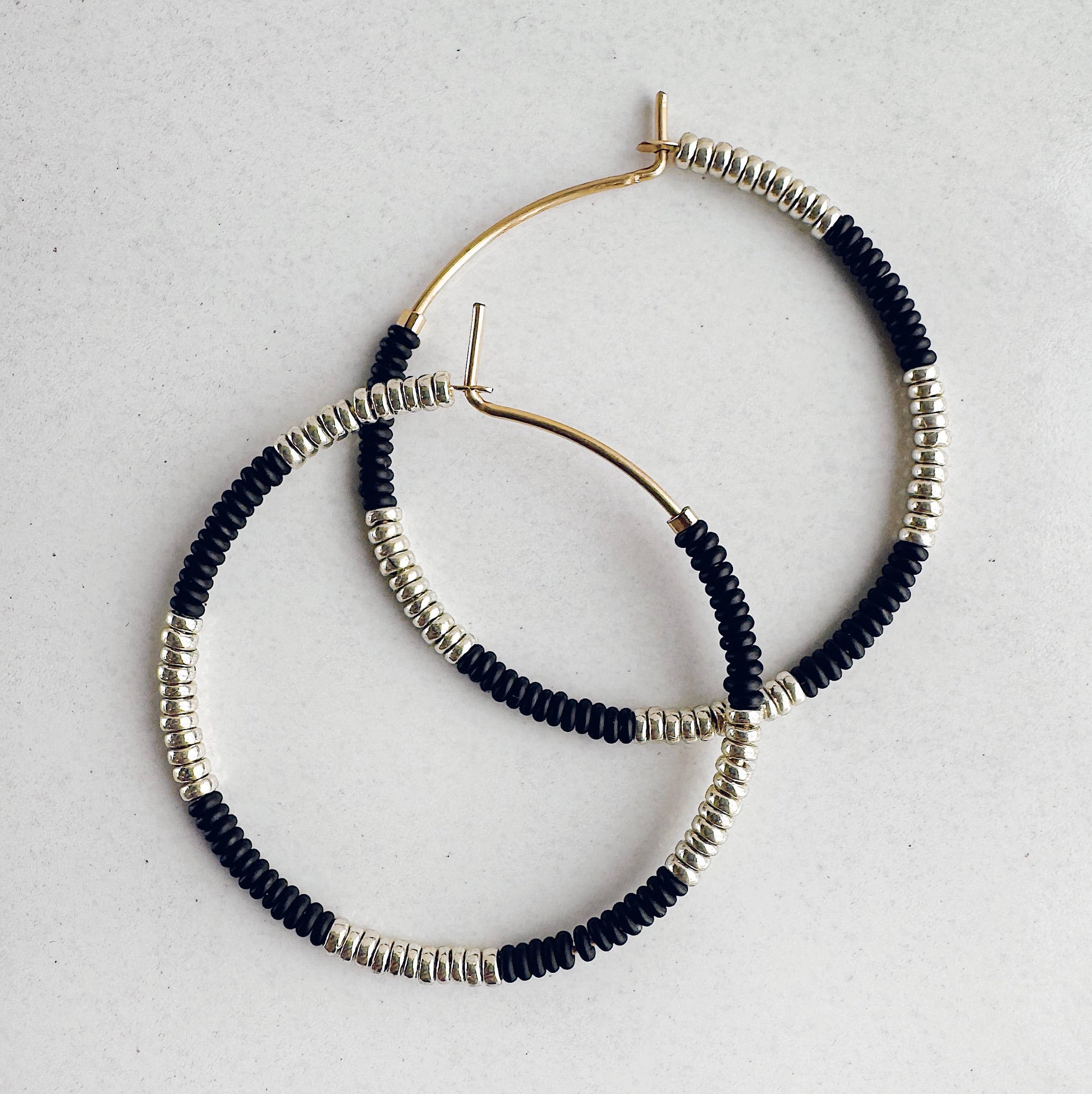 Hoop earrings with black and silver beads on a light gray background