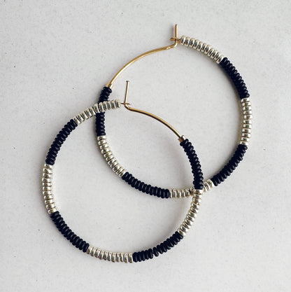 Hoop earrings with black and silver beads on a light gray background