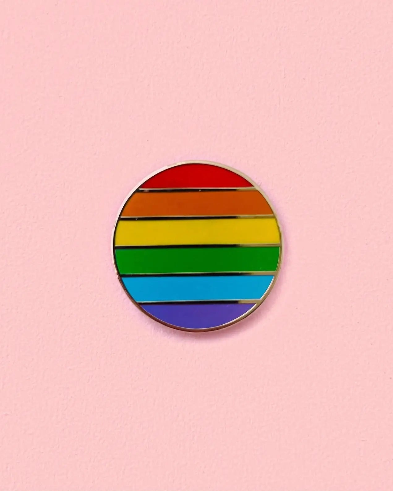 Round rainbow-colored pin on a pink background