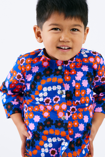 Child wearing a colorful floral Lilla Barn Clothing shirt on a white background