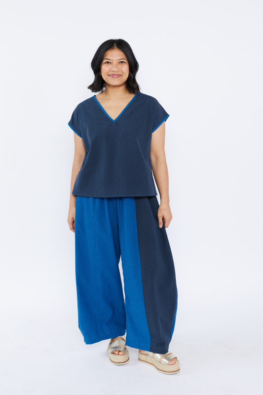 Woman wearing a blue and navy outfit from Lilla Barn Clothing on a white background