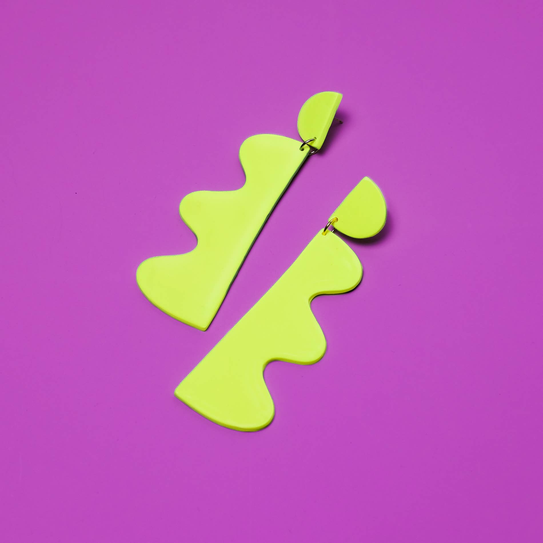 Pair of neon green earrings on a purple background