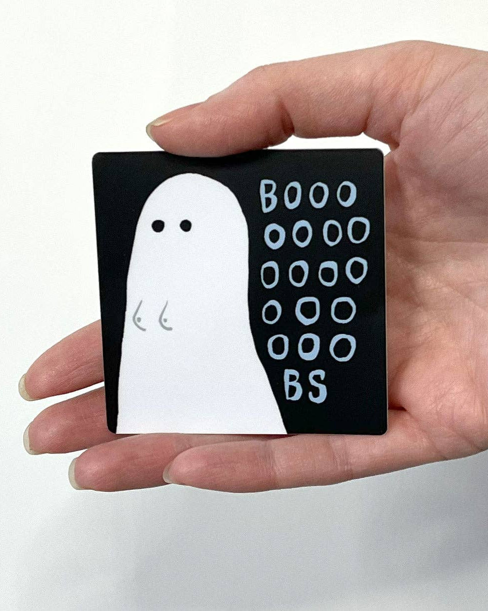 Hand holding a small black sticker with a white ghost illustration and 'BOOO OOOO BS' text.