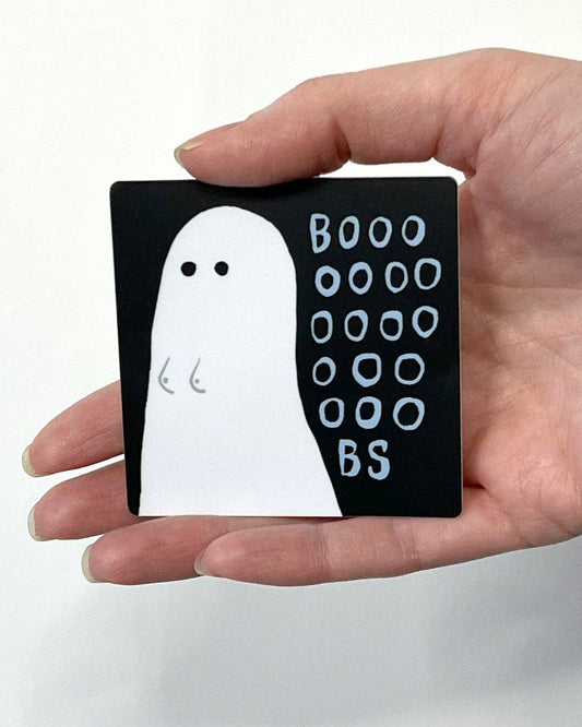 Hand holding a small black sticker with a white ghost illustration and 'BOOO OOOO BS' text.