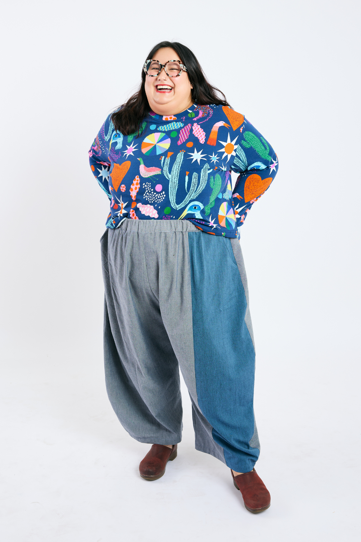 Person wearing a colorful patterned shirt and sustainable plus size wide-leg pants on a white background