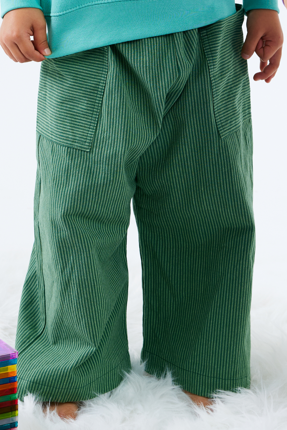 Green stripe cotton pants worn by a child on a white background