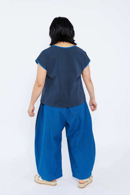 Person wearing a navy top and blue pants on a white background