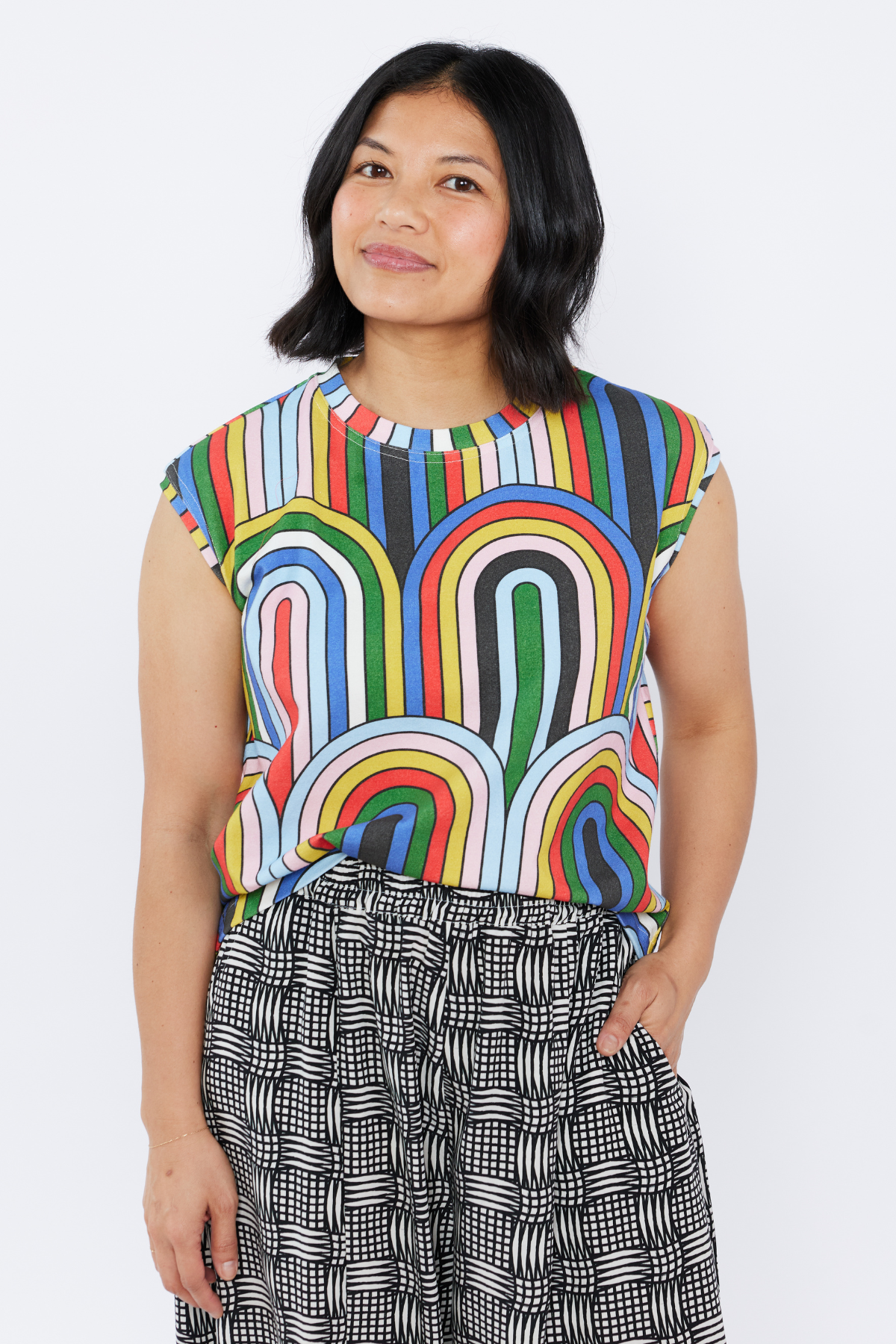 Woman wearing a colorful sleeveless top  by Lilla Barn Clothing with abstract patterns on a white background