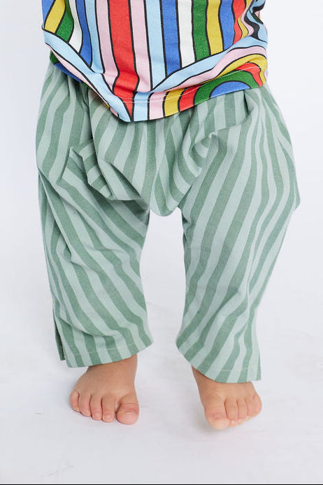 Child wearing a colorful striped shirt and green pants on a white background