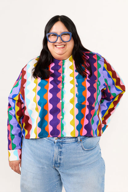 Plus Size Person wearing a colorful patterned shirt from Lilla Barn Clothing and blue jeans on a white background