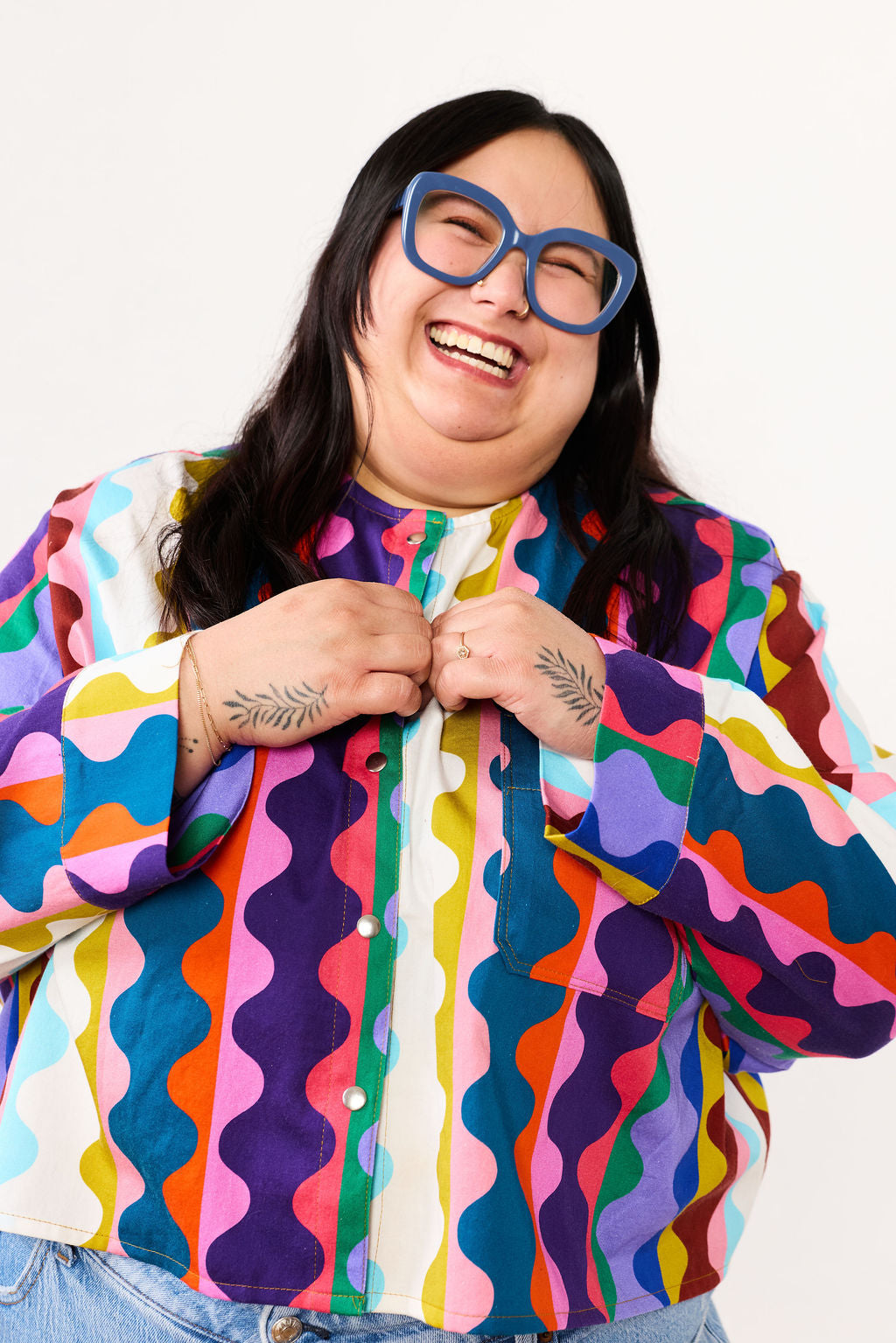 Person wearing a colorful Lilla Barn Clothing shirt with a white background